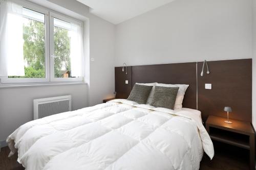 une chambre avec un grand lit blanc et deux fenêtres dans l'établissement Au Bord du Lac - Appt 6p vue lac et montagne, à Gérardmer