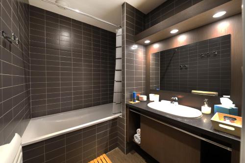 une salle de bain avec un lavabo, une baignoire et un miroir dans l'établissement Au Bord du Lac - Appt 6p vue lac et montagne, à Gérardmer