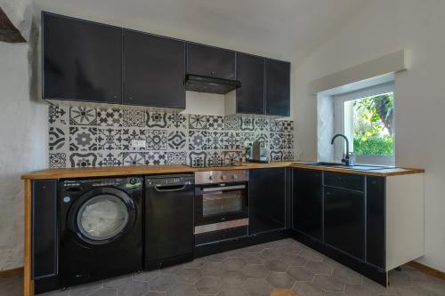 - une cuisine avec des armoires noires et un lave-linge dans l'établissement Maisonnette de charme, à La Colle-sur-Loup