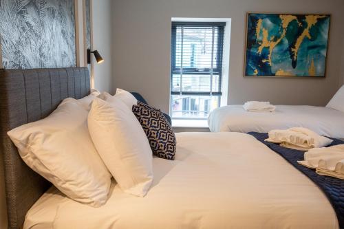 a bedroom with two beds with white pillows at The Abbeygate Townhouse in Galway