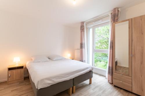 une chambre avec un lit et une grande fenêtre dans l'établissement Moulin à Vent A22 - Appt pour 4p, à Bondy