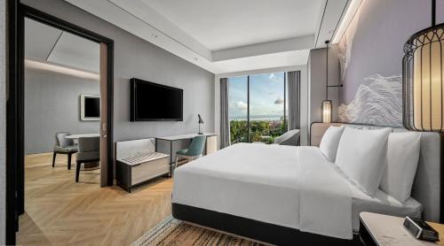 a bedroom with a large white bed and a desk at Hyatt Place Makassar in Makassar