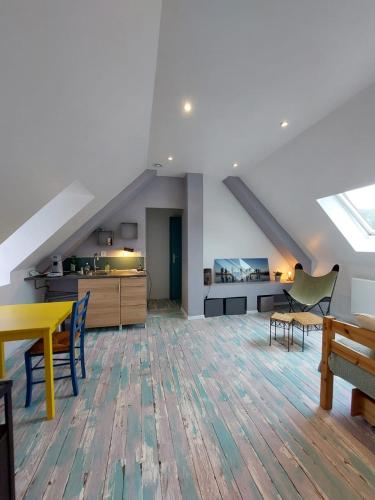 Cette chambre mansardée comprend une table, des chaises et une cuisine. dans l'établissement Appartement complet chez l'habitant, à Grand-Couronne
