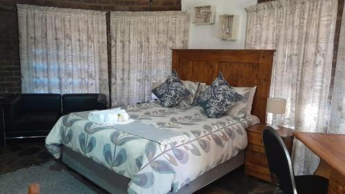 a bedroom with a bed and a desk and curtains at Maroela Gardens Guesthouse in Thabazimbi