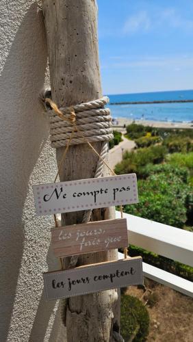 a wooden pole with signs on it next to the ocean at Studio plein sud le ciel le soleil et la mer in Palavas-les-Flots