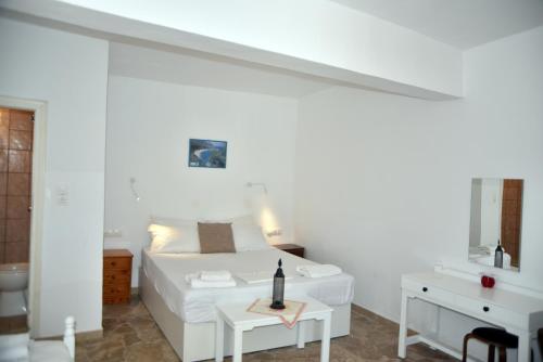 a white bedroom with a bed and a table at Jimmy's Apartments in Pythagoreio