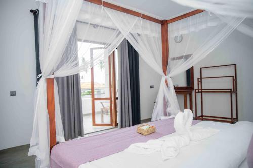 a bedroom with a bed with a canopy and a window at Hirigala Beach Resort in Ahangama