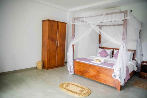 a bedroom with a canopy bed with pink pillows at Hirigala Beach Resort in Ahangama