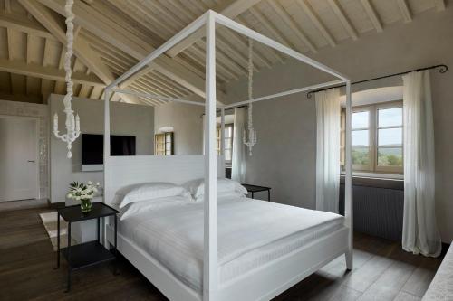 a bedroom with a white canopy bed and a table at COMO Castello Del Nero in Tavarnelle in Val di Pesa