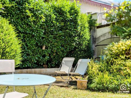 two chairs and a table in front of a hedge at Ô fil de l'eau - Jardin, Cabanon d'Antan, Parking in Olivet