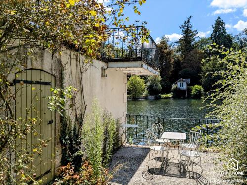 d'une terrasse avec une table et des chaises à côté d'une masse d'eau. dans l'établissement Ô fil de l'eau - Jardin, Cabanon d'Antan, Parking, à Olivet