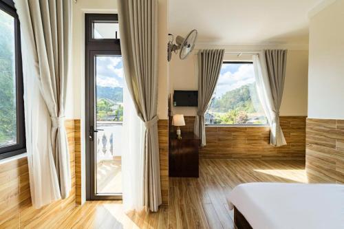 a bedroom with a bed and large windows at White Villa Đà Lạt in Da Lat