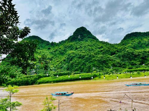 two boats on a river with mountains in the background at Son River House in Phong Nha