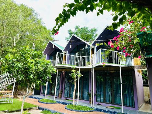 a house with a balcony and trees at Son River House in Phong Nha