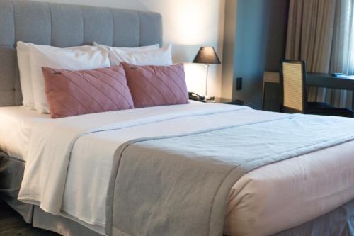 a bedroom with a large bed with pink and white pillows at Laghetto Stilo São Paulo in Sao Paulo