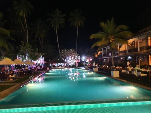 a swimming pool at night with palm trees and lights at Paradise Beach Club in Mirissa