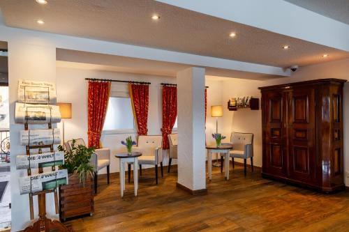 a dining room with tables and chairs and red curtains at Hotel Schloss Rheinfels in Sankt Goar