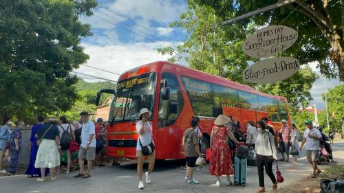 a group of people standing next to a red bus at Son River House in Phong Nha