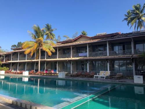 a hotel with a swimming pool in front of a building at Paradise Beach Club in Mirissa