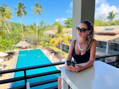 a woman sitting on a balcony looking at her cell phone at Paradise Beach Club in Mirissa