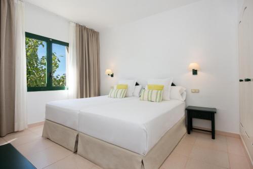 a large white bed in a white room with a window at Valentin Son Bou in Son Bou