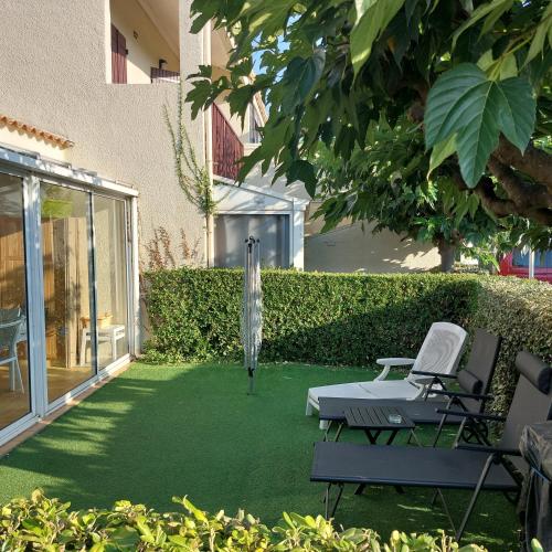 d'un jardin avec une pelouse dotée de deux chaises et d'un tapis de course. dans l'établissement Maison climatisée & wifi avec piscine, à Saint-Cyprien