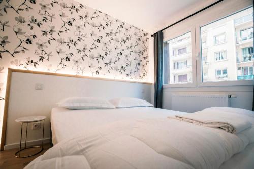 - une chambre avec un lit et un mur orné de fleurs dans l'établissement Le Majestic - T2 en centre ville, à Annecy