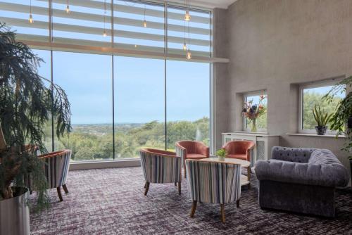a living room with a table and chairs and large windows at DoubleTree by Hilton Bristol South - Cadbury House in Yatton