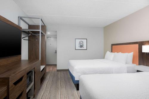 a hotel room with two beds and a flat screen tv at Hampton Inn Louisville Airport Fair/Expo Center in Louisville