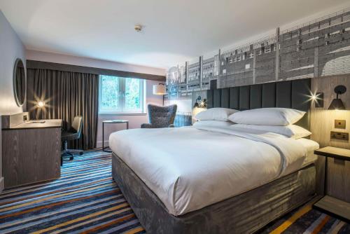 a hotel room with a large bed and a desk at DoubleTree by Hilton Bristol South - Cadbury House in Yatton
