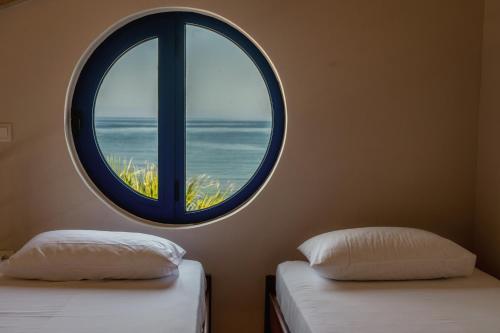 two beds in a room with a round window at Casa Azzura in Mytikas