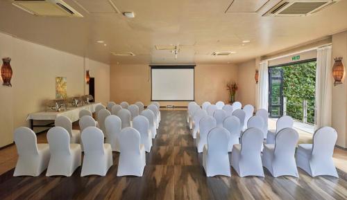 a conference room with white chairs and a screen at DoubleTree by Hilton Seychelles Allamanda Resort & Spa in Takamaka