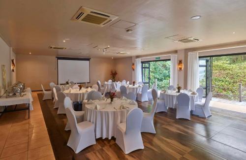 a banquet hall with white tables and white chairs at DoubleTree by Hilton Seychelles Allamanda Resort & Spa in Takamaka