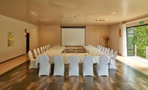 a conference room with a long table and white chairs at DoubleTree by Hilton Seychelles Allamanda Resort & Spa in Takamaka