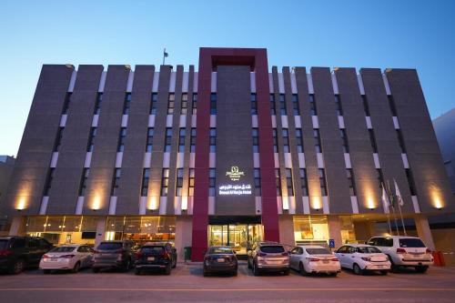 a building with cars parked in a parking lot at Snood Al Narjis Hotel in Riyadh