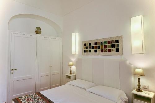 a white bedroom with a bed and two lamps at Braschi Amalfi Dreams in Minori