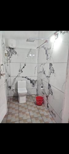 a bathroom with a toilet and a red bucket at JK Home stay in Sultan Bathery