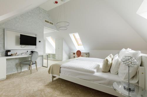 a white bedroom with a bed and a desk at Hotel Historia Malomkert in Veszprém