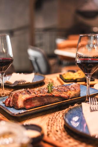 a table with two plates of meat and glasses of wine at Ona Lomas Village - La Manga Club in La Manga del Mar Menor