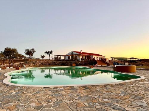 a swimming pool with a house in the background at Alpaca Farm And B&B - Mama Adama in Grândola