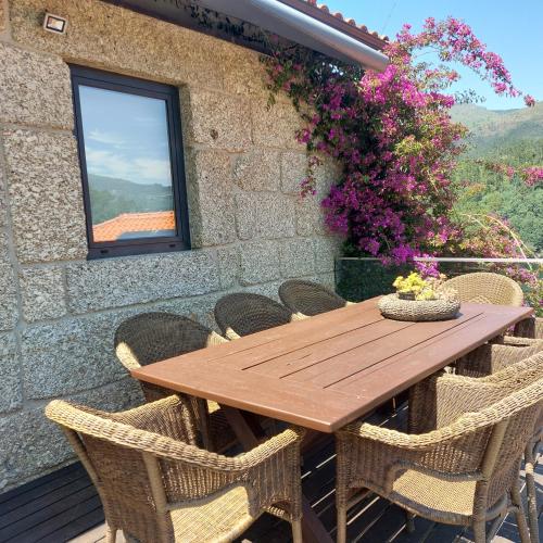 a wooden table and chairs on a patio with flowers at Casa do Penedo - Quinta de Fundevilla in Geres