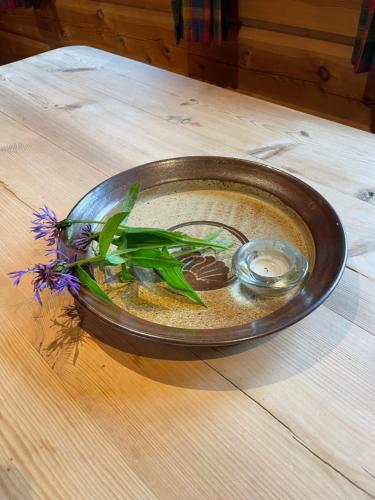 a bowl of liquid with a flower in it on a table at Rondane Sollia Friluftsliv Øvre Nordli in Sollia