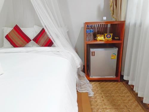 a bedroom with a bed with white sheets and a table at Aphilapa Residence in Chiang Mai