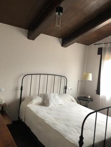 a bedroom with a bed with white sheets and a wooden ceiling at Casa Maragota, La casa de Portocelo in Jove