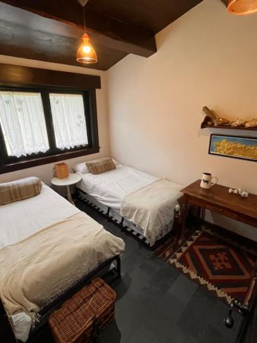 a bedroom with two beds and a table and a piano at Casa Maragota, La casa de Portocelo in Jove
