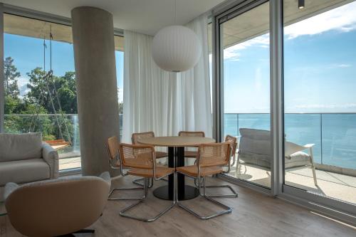 a living room with a table and chairs and windows at Green Cape Botanico in Batumi