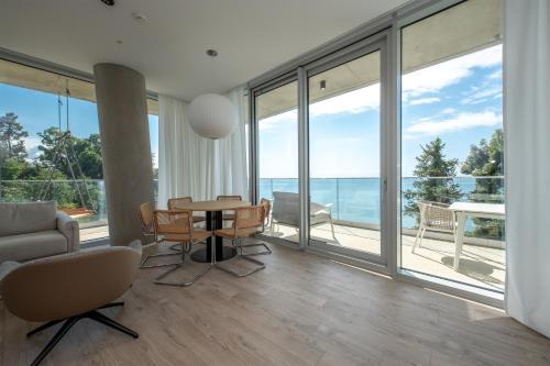a living room with a table and chairs and large windows at Green Cape Botanico in Batumi