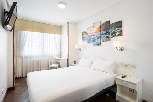 a hotel room with a white bed and a window at Hotel Alda Santa Cristina in Perillo