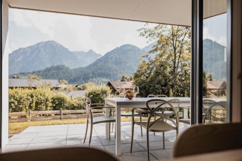 a table and chairs on a balcony with a view of mountains at Gutzeit-Appartements mit privater Infrarotkabine in Bad Hindelang