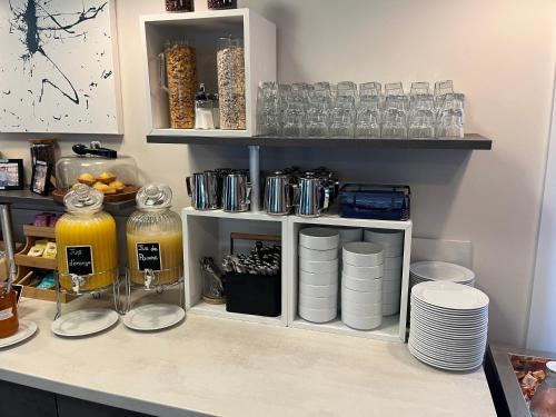 a kitchen counter with a shelf with plates and glasses at Hotel Caiman in Pierrelatte